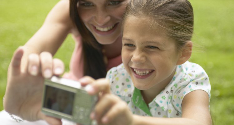 Mother and daughter (7-9) taking photograph with digital camera