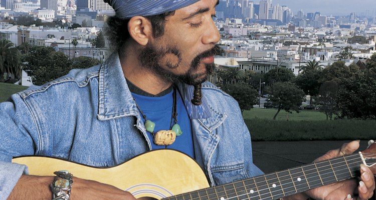 Mature Man With Funky Beard Playing Acoustic Guitar Against San Francisco Cityscape