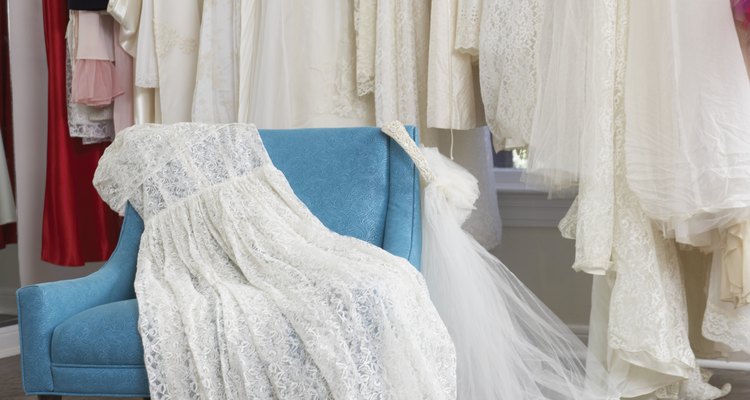 Wedding dress and veil on armchair in clothing store