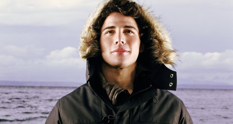Young man standing beside sea, wearing hooded jacket, portrait