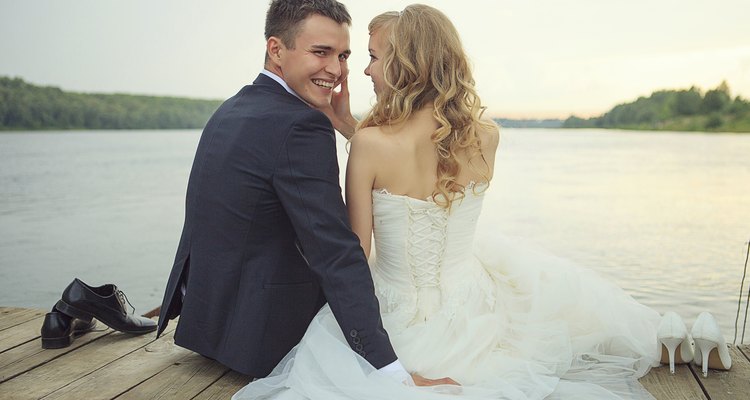 Bride with the groom sitting on a pier