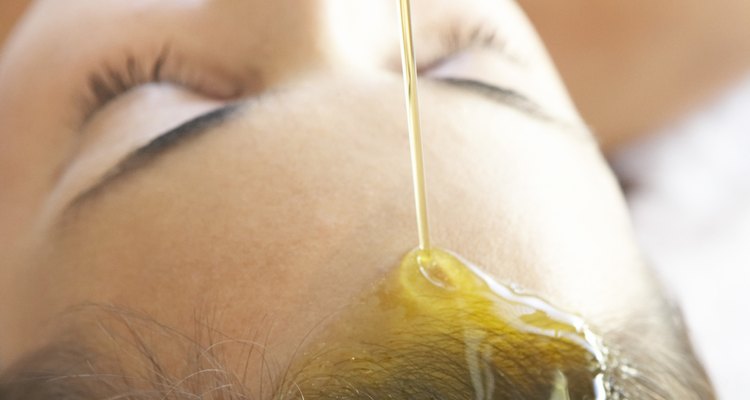 Oil pouring onto woman's forehead and hair