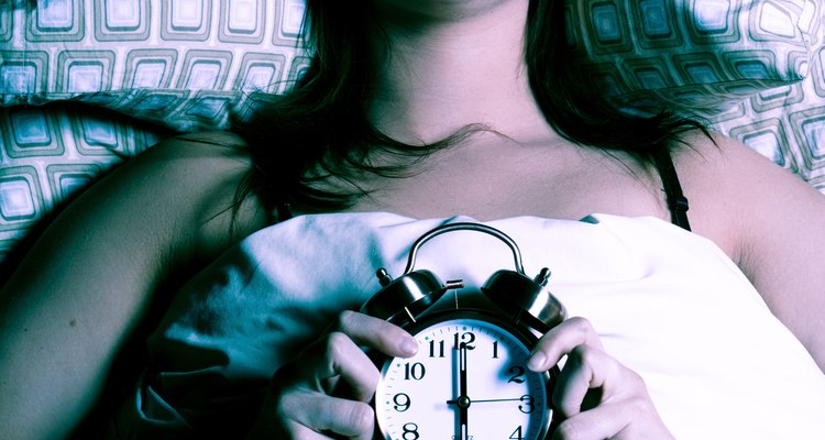 Woman in bed holding alarm clock