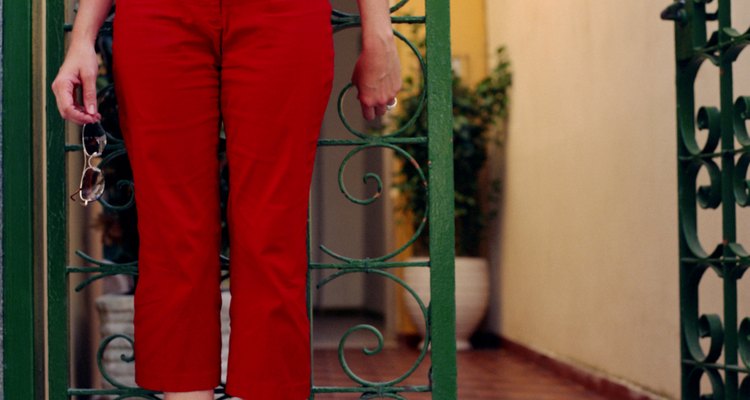 Woman in red capri pants standing by gated doorway