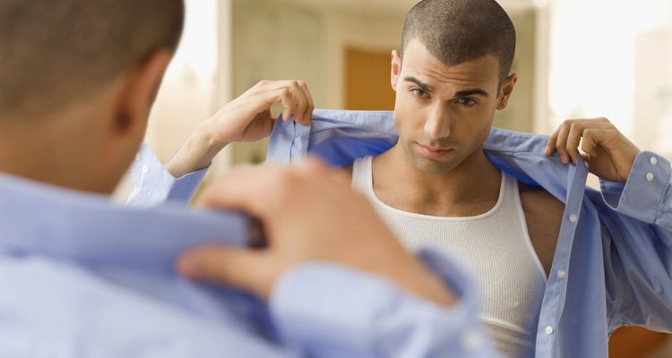 Hispanic man putting on shirt