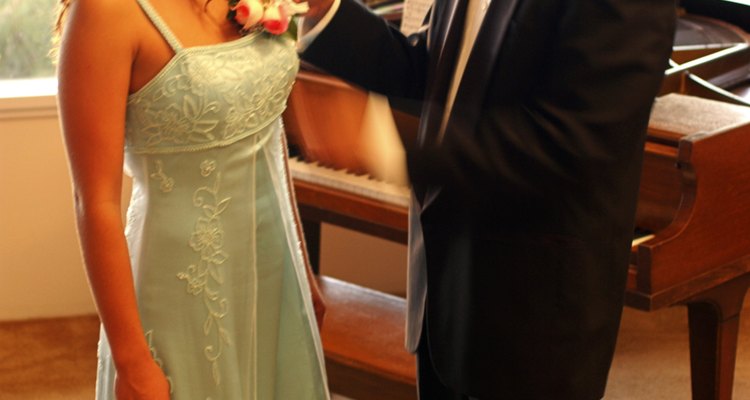 Teenage boy pining corsage on teenage girl