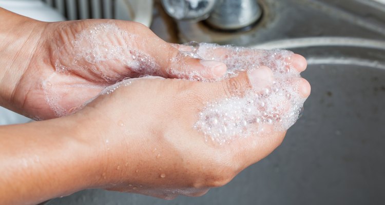 Woman washing her hands with soap over sink