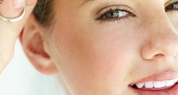 Close-up of a young woman tweezing her eyebrows