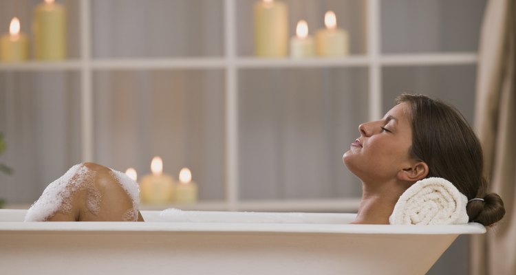 Content woman lying in bathtub with candles