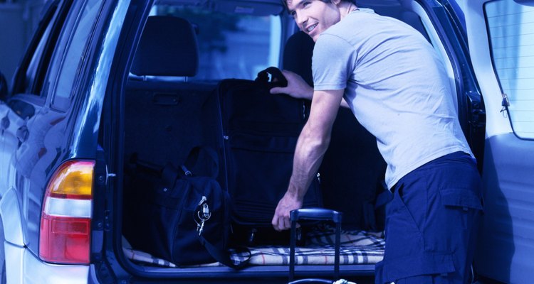 tungsten shot of a young man offloading luggage from the back of car