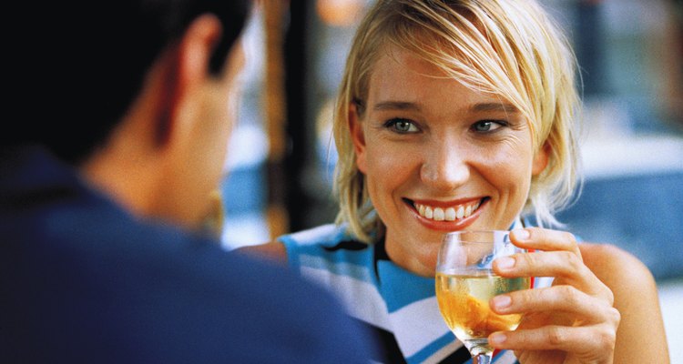 close-up of a woman holding a glass of wine and smiling at a man