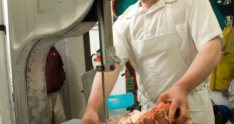 Butcher using saw to cut ribs at slaughterhouse