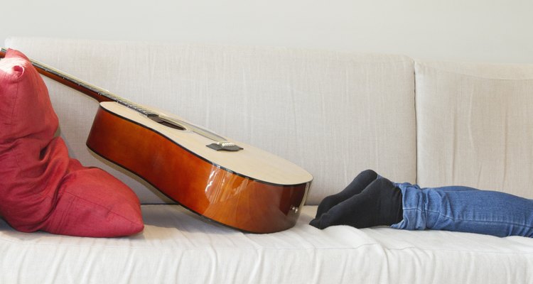 Low section of man's leg with guitar kept on sofa