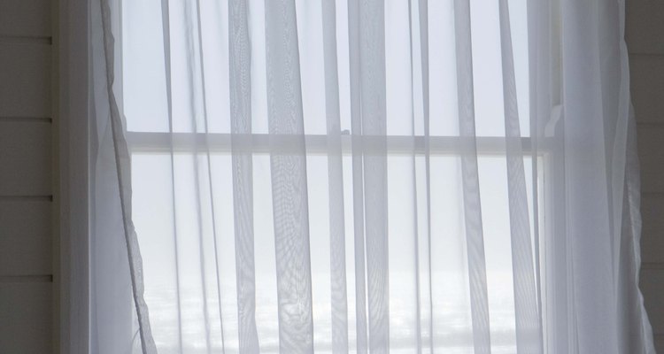 Las cortinas transparentes dejan pasar la mayoría de la luz a una terraza acristalada.