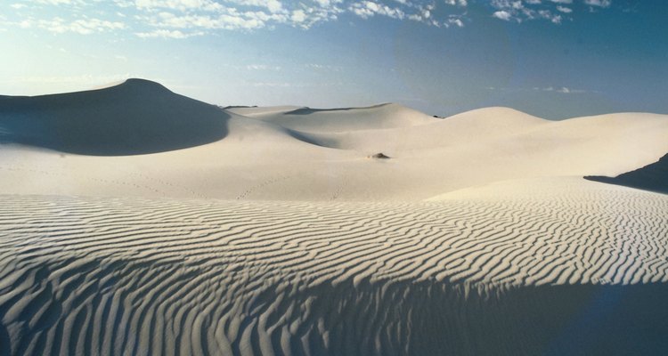 Sand dunes are created when sand is deposited by the wind.