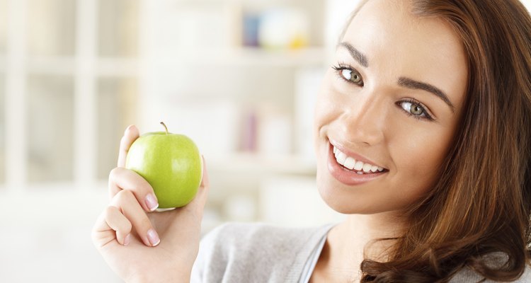 Pretty healthy young woman smiling holding a green apple