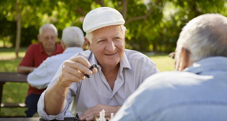 Active retired people, two senior men playing chess at park