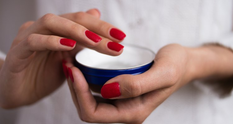 Hands to apply the cream out of the blue jar