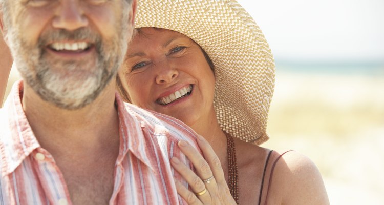 Mature couple laughing, portrait (focus on woman wearing straw hat)