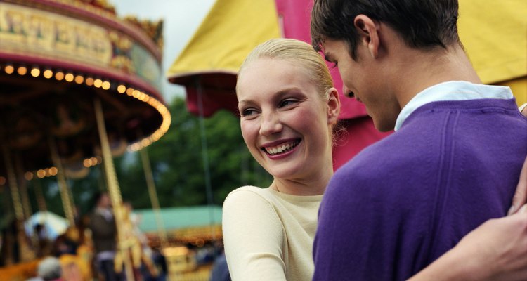 Young couple embracing at fairground, smiling, close-up