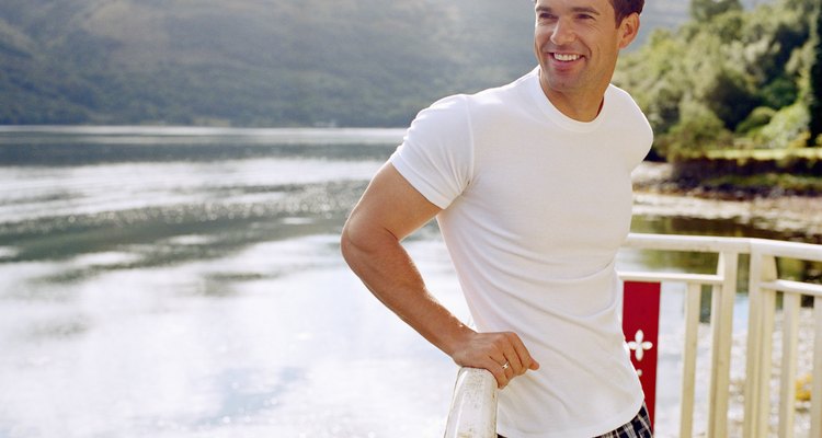 Man leaning on railing by water, smiling