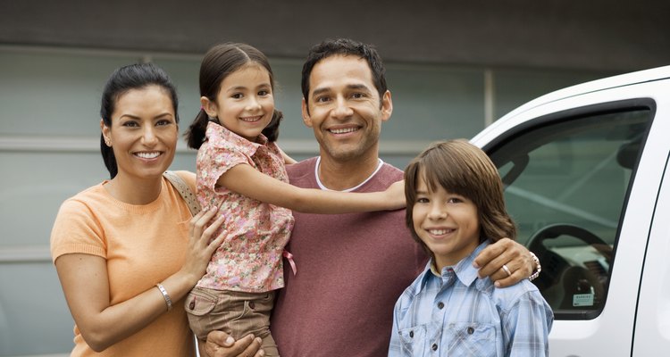 Family standing outside house next to car