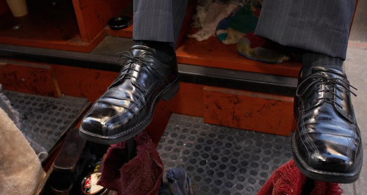 Man sitting on shoeshine chair, close-up, low section