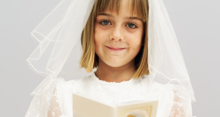 Close-up of a girl (11-13) wearing her first holy communion dress and holding prayer book