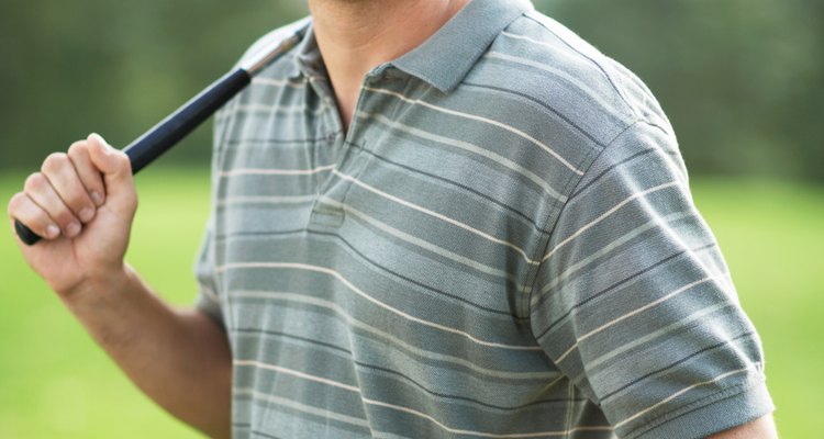 Man holding golf club, smiling