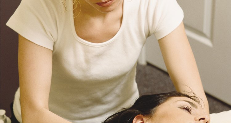 a caucasian woman massages the neck of a relaxed client