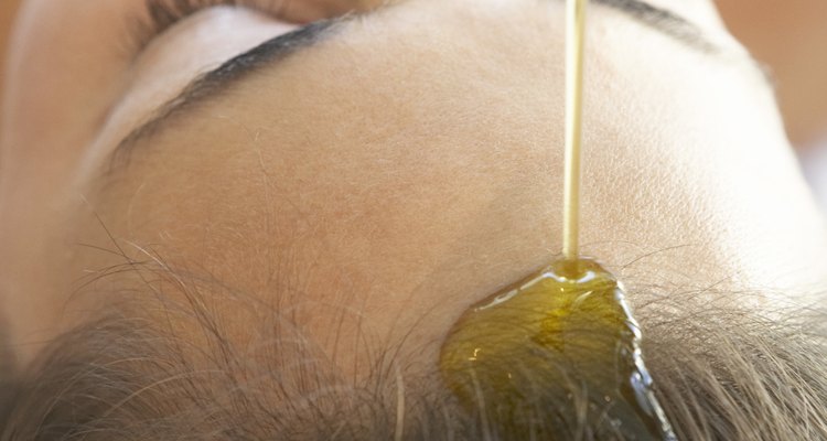 Oil pouring onto woman's forehead and hair