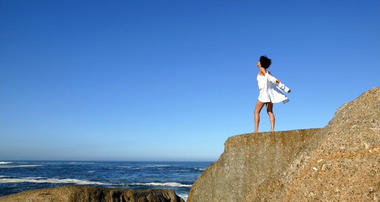 Woman standing on cliff by seashore