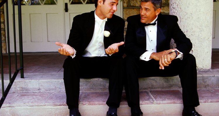 view of two men dressed in tuxedos sitting on the stairs and talking