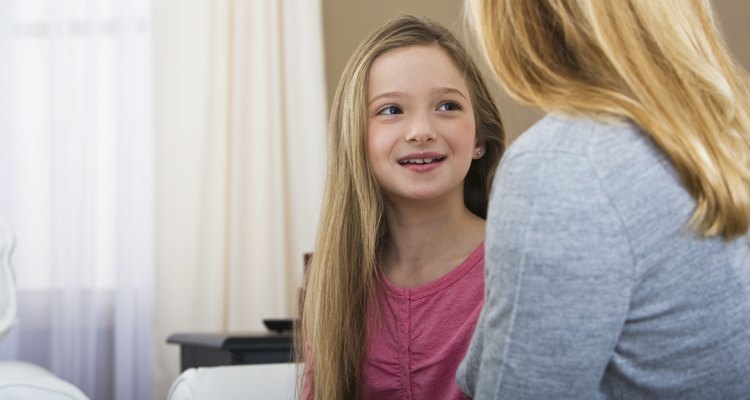 Una niña sonrie mientras escucha a su madre.