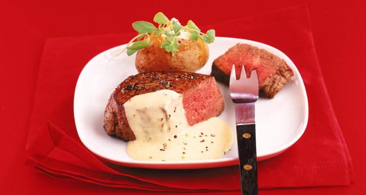 Roasted meat and savory sauce with fork on plate, close-up