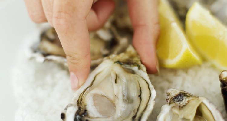 Close-up of a young woman's hand picking an oyster from a bed of ice