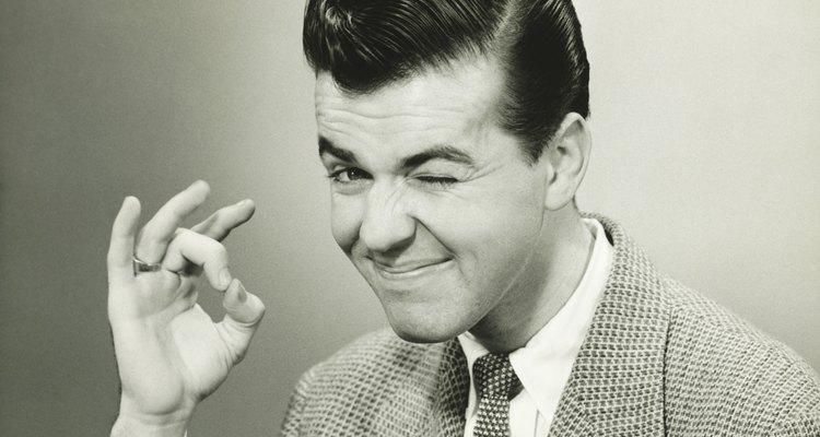 Man making OK gesture, winking in studio, (B&W), portrait