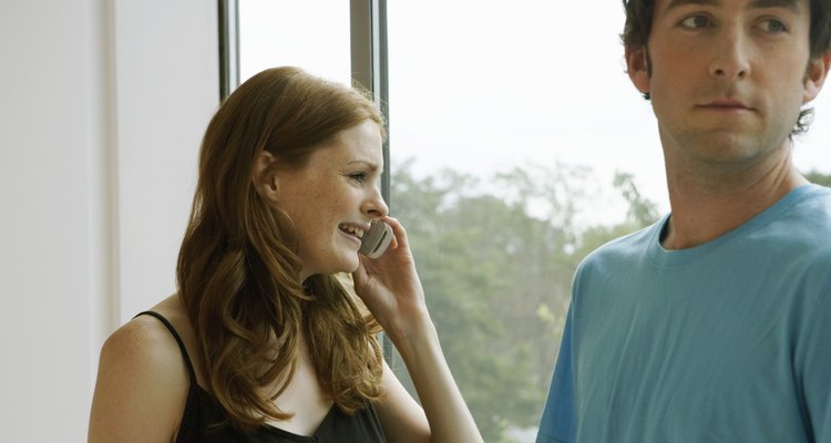 Young couple by window, woman using mobile phone, close-up