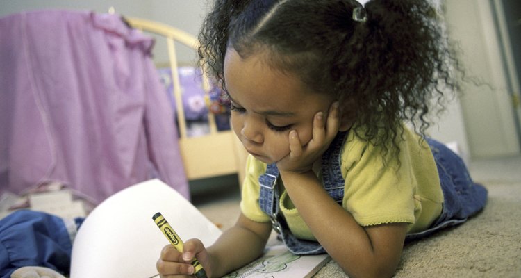 Girl coloring with crayons in a coloring book