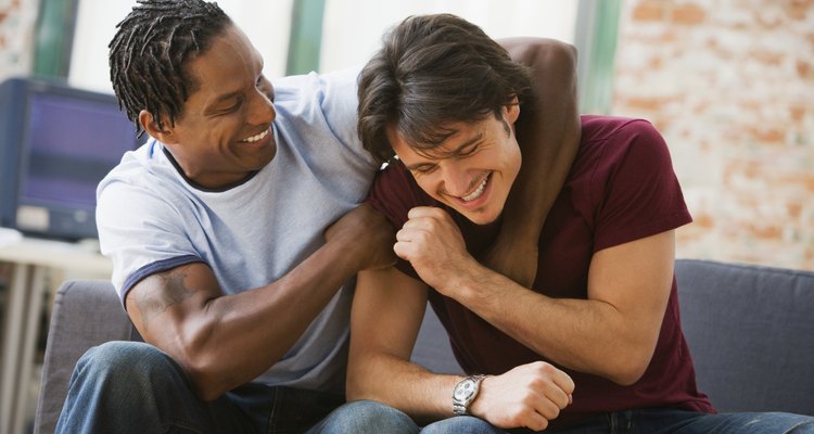 Multi-ethnic men hugging on sofa