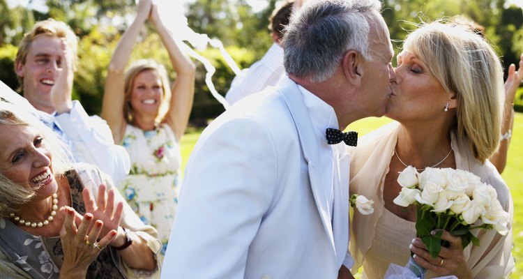 Bride and groom kissing wedding guests in background