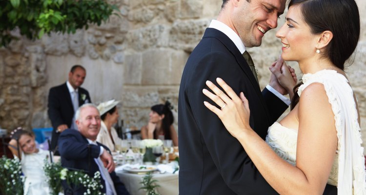 Bride and groom dancing, wedding party in background