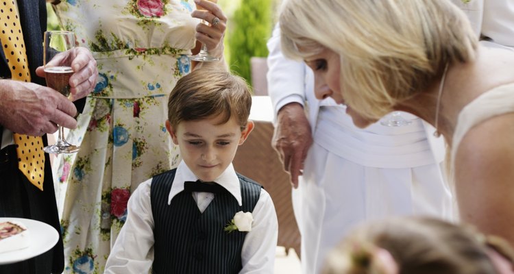 Bride serving wedding cake to pageboy (6-7) and guests