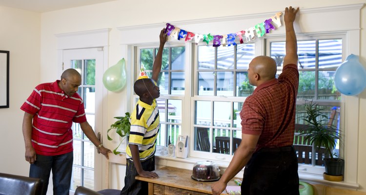 Men and boy hanging birthday decorations