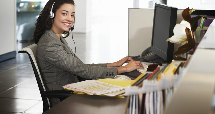 Businesswoman wearing headset at desk, smiling, portrait