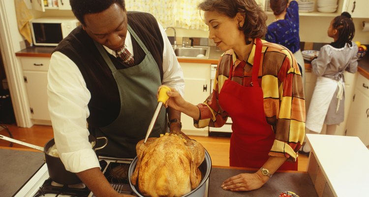 Couple basting thanksgiving turkey