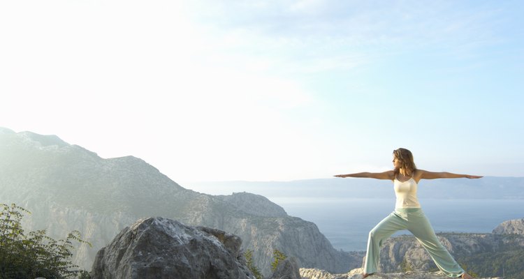 Young woman performing stretching exercises on rock near sea