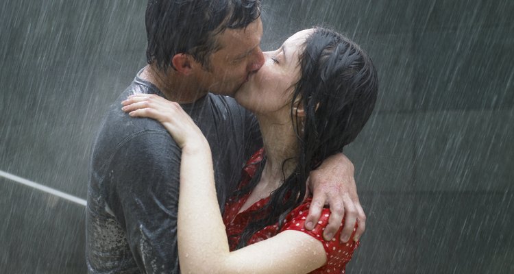 Couple kissing in rain, side view, close-up