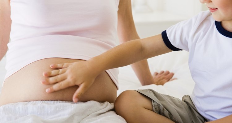 Menino tocando a barriga grávida da mãe