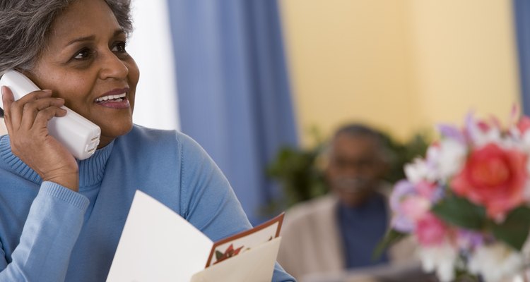 Woman reading greeting card and talking on telephone